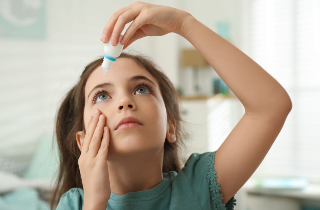 An image of a child putting eye drops in their eyes by themselves.