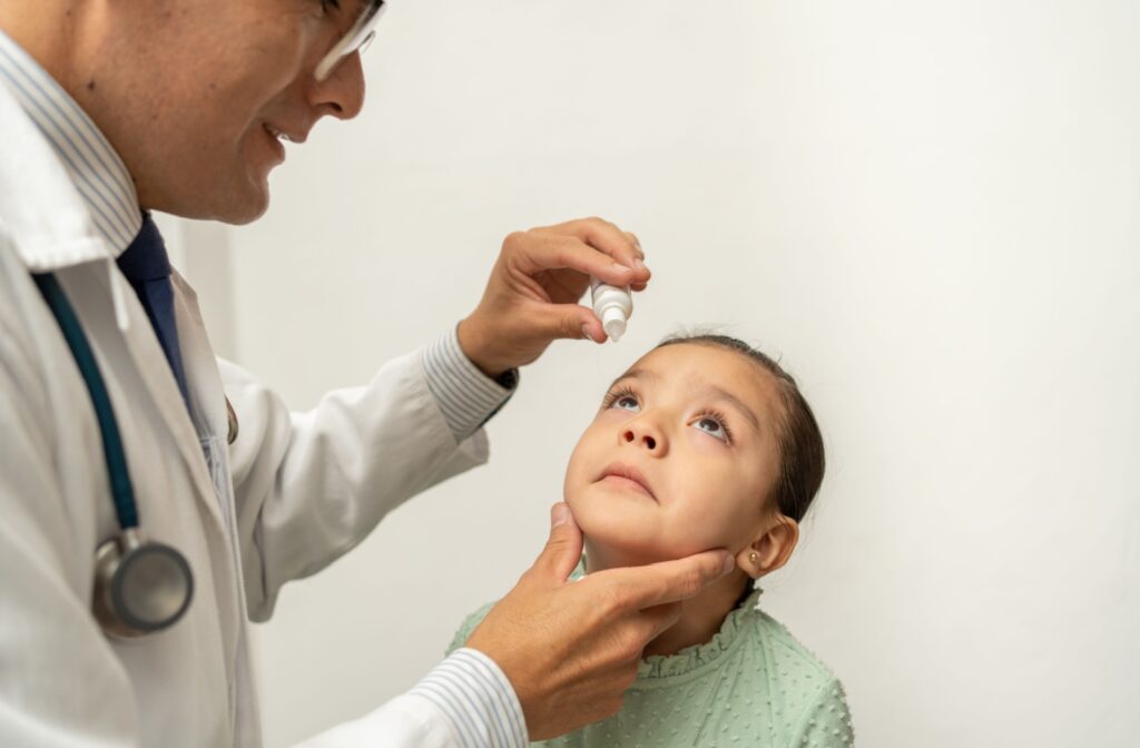 An eye doctor places the correct dosage of medicated eye drops in their young patient's eyes.