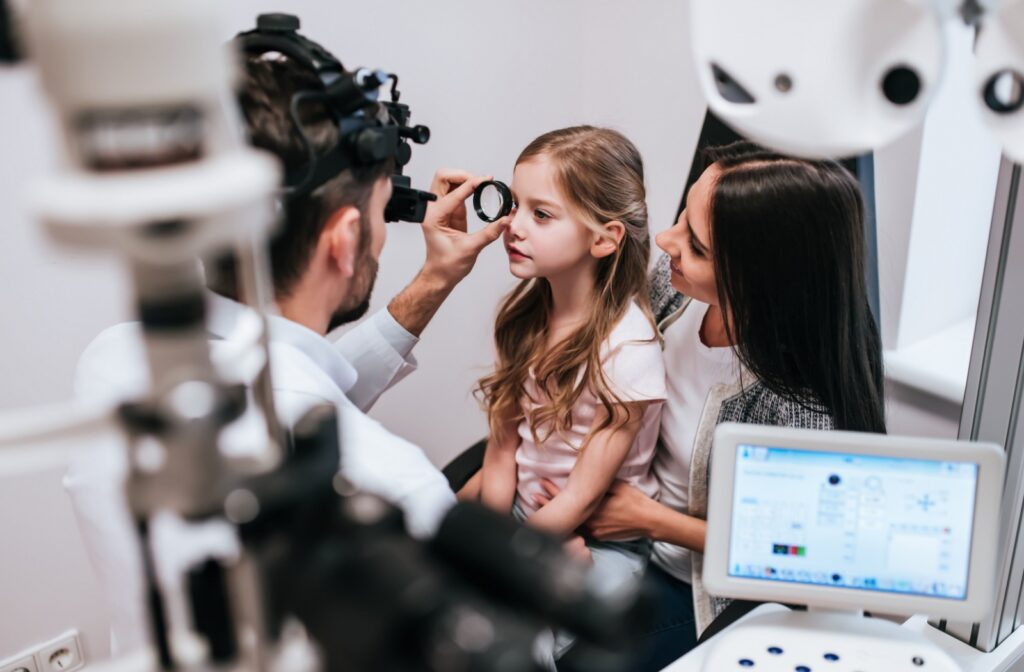 A parent sits with their child as they get a comprehensive eye exam to determine if they have myopia.