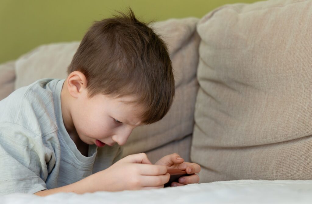 A child struggles to see their cellphone without holding it close to their face.