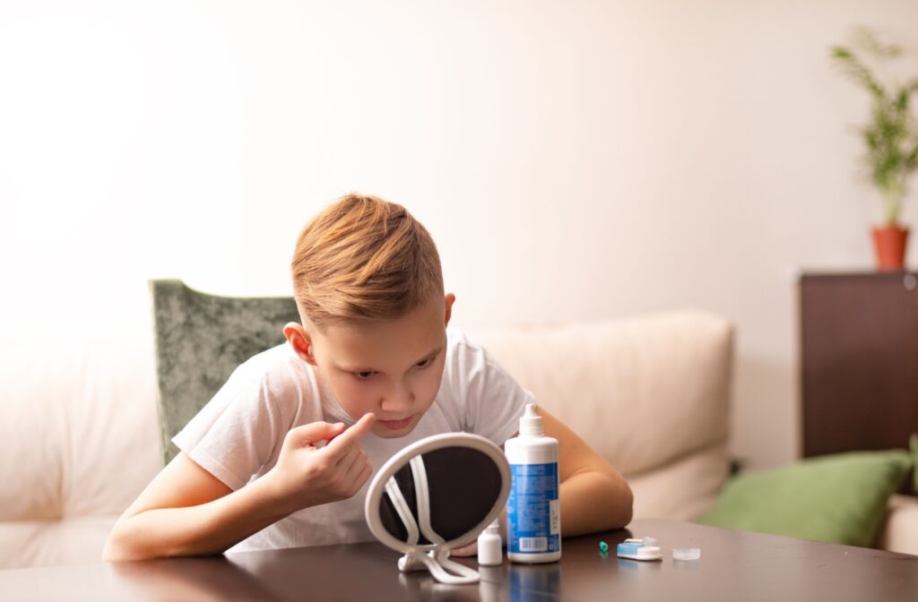 An image of a child lookin in a small mirror as they put their soft contact lenses in.