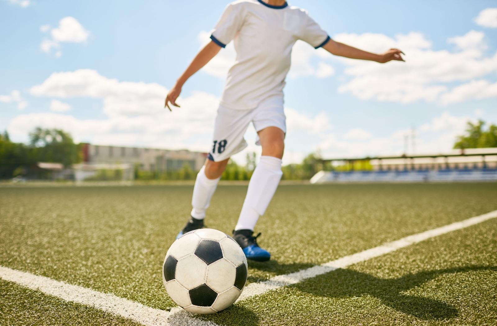 A child gearing up to kick a soccer ball on a grassy field