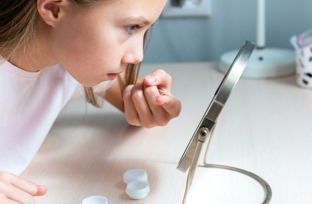 A child looking in a mirror to put their contact lens in their eye